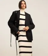 Vestido midi de punto con cuello alto y mangas largas. Diseño recto con rayas horizontales negras sobre fondo crudo y aberturas laterales.
