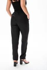Conjunto negro de top corto con breteles anchos y pantalón de vestir de tiro alto con botón dorado.