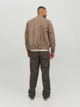 Campera bomber color marrón claro de cuero sintético, con cuello tipo baseball, cierre frontal con cremallera, bolsillos laterales con cremallera y bolsillo en la manga.