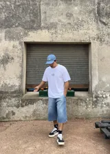 Remera blanca de algodón con corte boxy y parche bordado con la palabra "Brokers" en óvalo azul y verde.