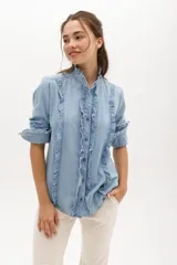 Camisa celeste de manga larga con detalles de volados en el frente y cuello mao.
