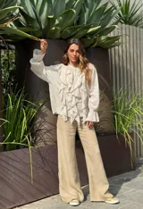 Camisa beige de manga larga con volados frontales y puños elastizados.
