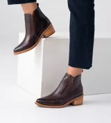 Bota corta de cuero negro con puntera fina, cierre lateral y detalle de cuero con textura de cocodrilo en la parte delantera.