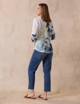 Buzo blanco estampado con flores azules y detalles en verde y amarillo, de la marca Milano. Tiene cuello redondo y mangas 3/4 con apliques de brillos en el frente.