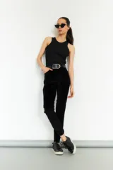 Pantalón de pana negro, corte slim, con cintura alta y cierre frontal con botón y cremallera.