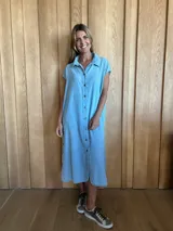 Túnica celeste de corte recto, con cuello camisero, mangas cortas, botones frontales y tajos laterales.