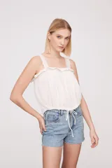 Musculosa blanca con breteles finos y detalles de puntilla.