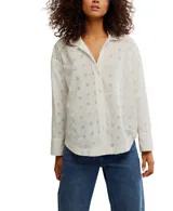 Camisa blanca de algodón con bordado calado, corte relajado, cuello con muescas, cierre frontal con botones, mangas largas con hombros caídos y puños.