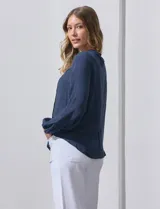 Blusa azul marino de manga larga con cuello redondo con detalle de broderie y cierre frontal con botones.