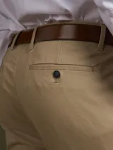 Pantalón de vestir azul marino, de corte slim fit, con bolsillos laterales y traseros. Se ajusta a la cintura con cinturón de cuero marrón.