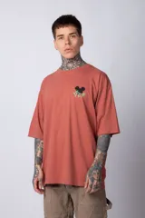 Remera blanca de algodón de corte oversize con mangas cortas y cuello redondo. Presenta un pequeño estampado en el frente con la figura de Mickey Mouse y caracteres orientales.