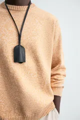 Sweater color arena con textura jaspeada, de corte recto, cuello redondo y mangas largas con terminaciones acanaladas.