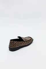 Mocasines negros de símil cuero texturizado, con punta cuadrada, detalle de bordado a tono en la capellada y taco de 2,5cm.