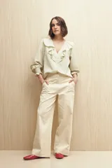Camisa blanca a rayas verticales, con escote en V, mangas 3/4 con puños elastizados y volados.