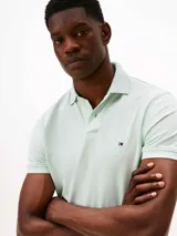 Chomba celeste de Tommy Hilfiger, modelo 1985, de corte regular, con cuello tipo chomba, cartera de dos botones, logo de Tommy Hilfiger bordado en el pecho y mangas cortas.