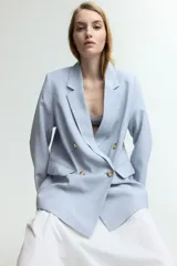 Blazer celeste de doble botonadura con solapas de muesca, hombreras y bolsillos delanteros ribeteados con solapa.