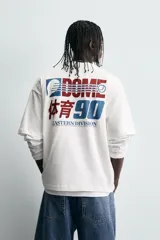Camiseta blanca de corte relaxed fit, cuello redondo y manga corta. Estampado frontal con diseño gráfico en azul y rojo con texto en chino y la leyenda "Eastern Division 90".