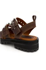 Sandalia de cuero color marrón chocolate, con dos tiras anchas sobre el empeine ajustables con hebillas metálicas plateadas.