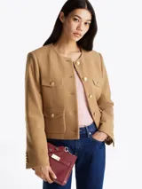 Cartera satchel color borgoña con asa superior y correa bandolera extraíbles y ajustables. Presenta cierre magnético, dos compartimentos principales y un compartimento interior con cremallera. Decorada con tachuelas metálicas en el asa y el cuerpo, y logo TH en la parte delantera.