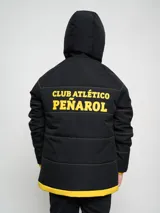 Campera gris con capucha y cierre frontal, con costuras horizontales y logo del Club Atlético Peñarol en el pecho.