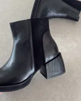 Botines negros de cuero vacuno, con paneles de cuero liso y gamuza.