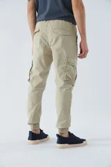 Pantalón cargo color marrón con corte slim, elástico en cintura y cordón ajustable, bolsillos cargo con botones y puños elásticos. Confeccionado en algodón y spandex.
