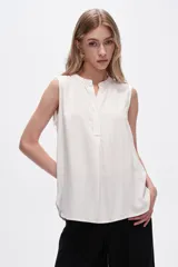 Blusa viscosa color blanco, corte evasé, con cuello a la base y sin mangas.