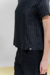Blusa de lino color beige con rayas verticales negras, corte recto, escote redondo y mangas cortas.
