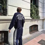 Suéter de tejido grueso color azul marino, corte oversize con hombros caídos y estampado gráfico grande en la espalda con tipografía workwear/heritage.