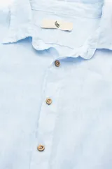 Camisa celeste de lino con botones de coco y corte recto.