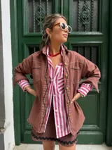 Camisa oversize a rayas verticales rojas y blancas, de algodón, con cuello camisero, mangas largas con puños abotonados y bolsillo en el pecho.