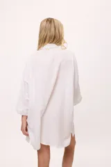 Vestido camisero a rayas verticales de colores pastel, con cuello camisero, cierre frontal con botones y mangas largas.