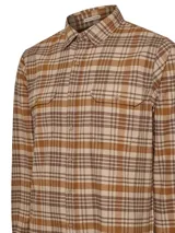 Camisa de franela a cuadros azul, beige y negro, de manga larga con puños abotonados, cuello camisero y cierre frontal con botones de madera. Tiene dos bolsillos de parche con botón en el pecho. Confeccionada en algodón orgánico cepillado.