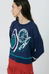 Buzo azul marino tejido en jacquard con diseño de frutas y verduras. Tiene mangas tejidas en ochos, bordado en la espalda y puños con agujerito para el dedo.