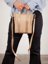Bolso tipo tote de cuero color beige con detalles dorados en las asas y correa.