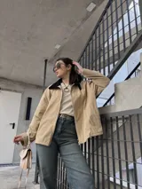 Campera de pana color beige con cierre frontal y cuello negro.
