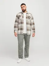 Sobrecamisa a cuadros beige, marrón y blanco, de manga larga y cuello camisero con fit confort. Cierre con botones y bolsillos en el pecho con solapa y broche. Estilo plus size diseñada para cuerpos de talla grande. Tejido de sarga resistente con patrón en “V” característico.