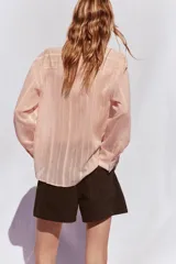 Camisa color salmón con rayas verticales, de cuello solapa y manga larga.