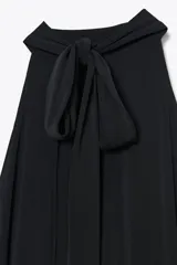 Vestido largo negro, corte recto, con cuello halter que se ata en la nuca y espalda descubierta.