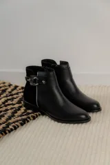 Bota corta negra de cuero con detalle de hebilla metálica y elástico en el tobillo.