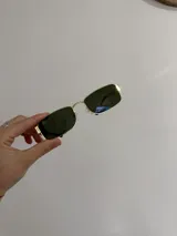 Lentes de sol rectangulares con montura dorada y cristales negros.