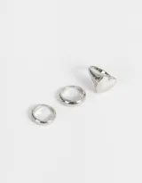 Set de tres anillos dorados de metal con diferentes diseños: uno liso, uno con forma de corazón y uno con forma de domo.