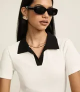 Blusa blanca acanalada de rib con cuello polo negro contrastante y mangas cortas.