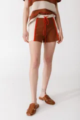 Short tejido en jersey color marrón con detalles de rayas verticales en color crema y ribete naranja.