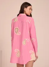 Camisa rosada de manga larga con cuello clásico y cierre frontal con botones. Presenta bordados de encaje color crema en forma de paisley en la parte superior delantera y en las mangas.