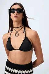 Top de bikini blanco con tirantes finos ajustables al cuello y a la espalda. Presenta volados en el escote y está confeccionado en tejido suave con acabado elástico.