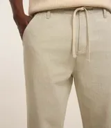 Pantalón relaxed de hombre confeccionado en tejido oxford de algodón color beige, con trabillas en la cintura y cordón para lazo.