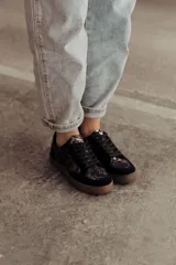 Zapatillas bajas color beige con estampado de piel de serpiente metalizada, cordones blancos y suela color caramelo.