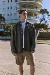 Camisa de denim negra de manga larga con cuello clásico y cierre con botones. Diseño amplio con bolsillos en el pecho.