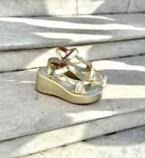 Sandalias doradas con plataforma, tiras cruzadas y hebilla al tobillo.